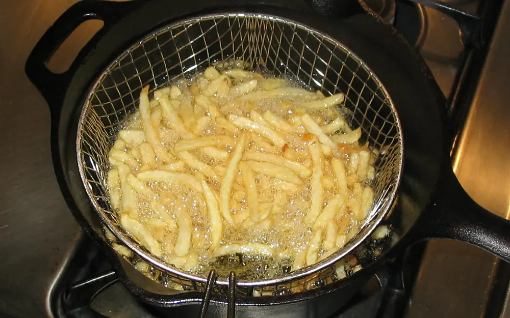 Pommes im Frittierkorb in heißem Öl